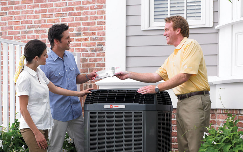 trane dealer and couple standing over ac unit